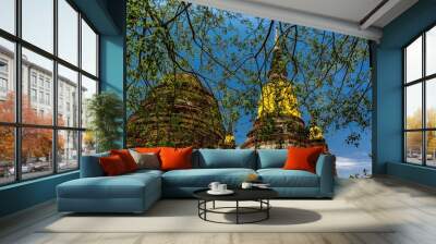 Wat Yai Chai Mongkhon Buddhist temple in Phra Nakhon Si Ayutthaya, Thailand behind green tree leaves Wall mural