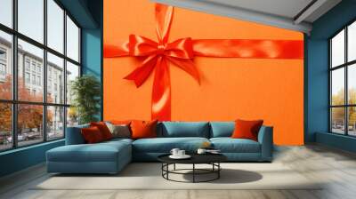 Orange ribbon and bow on an orange background. The concept of gifts. Wall mural