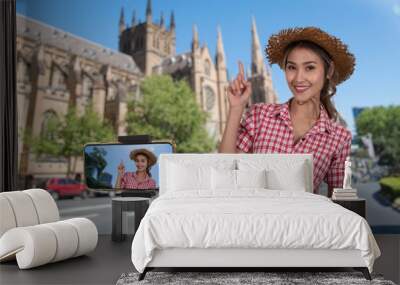 Outdoor shot of female travel blogger taking video clip with mobile phone on stabilizer tripod. Wall mural