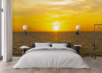 Front view in the blue ocean in the evening, the sun was setting, reflections fell on the smooth calm surface with golden warm light. The sky is clear and clean. Feeling refreshed and relaxed. Wall mural