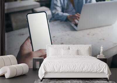 Mockup image blank white screen cell phone.man hand holding texting using mobile on desk at coffee shop.background empty space for advertise text.people contact marketing business,technology  Wall mural