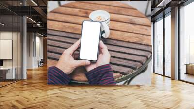 Mockup image blank white screen cell phone.man hand holding texting using mobile on desk at coffee shop.background empty space for advertise text.people contact marketing business,technology Wall mural