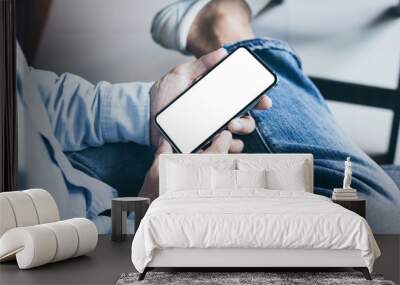 Mockup image blank white screen cell phone.men hand holding texting using mobile on sofa at home office.background empty space for advertise text.people contact marketing business and technology  Wall mural