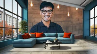 portrait young asian man wear eye glasses smiling cheerful look thinking position with perfect clean skin posing on cafe background.fashion people life style concept Wall mural