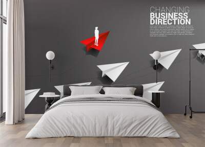 Silhouette of businessman standing on red origami paper airplane is move apart direction from group of white. Business Concept of disruption and niche marketing Wall mural