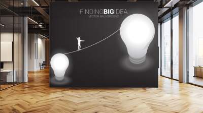 Silhouette of businessman walking on rope walk from small bulb to big one.Concept for business risk for finding big idea and design thinking Wall mural