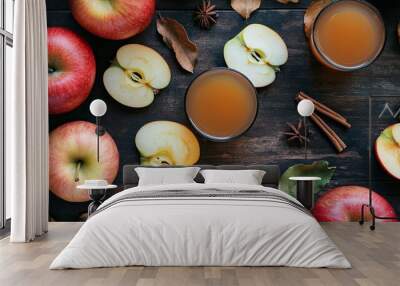 A flat lay of apple juice with fresh apples, slices, and cinnamon sticks placed neatly on a dark wooden surface, highlighting the rich colors of the drink. Wall mural