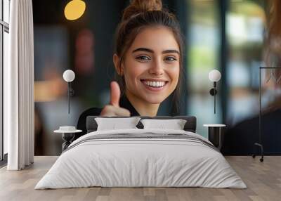 A happy young office worker, dressed smartly, giving a thumbs up to a colleague, showing approval and a positive attitude in the workplace. Wall mural