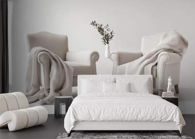 A pair of armchairs with one draped in a soft wool blanket and the other in a light linen throw, both displayed against a pristine white background, exuding coziness. Wall mural