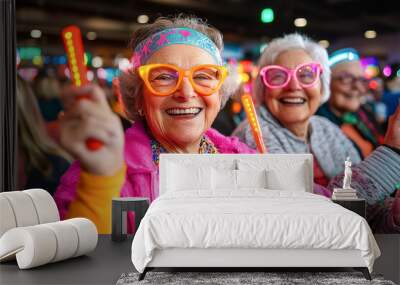 A group of elderly women are seen having a wonderful time, joyfully engaging at a lively event with colorful accessories and glowing sticks, embodying happiness. Wall mural