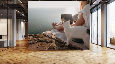 Woman sea laptop. Business woman petting cat and working on laptop by the sea. Close up on hands of pretty lady typing on computer outdoors summer day. Freelance, digital nomad and holidays concept. Wall mural