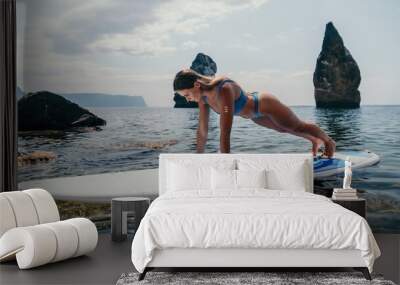 Woman sup yoga. Happy sporty woman practising yoga pilates on paddle sup surfboard. Female stretching doing workout on sea water. Modern individual female hipster outdoor summer sport activity. Wall mural