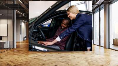 African man with a girl in a car dealership choose a new car Wall mural