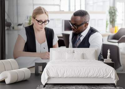 Business woman enters into a contract with an African man sitting at a table in the office Wall mural