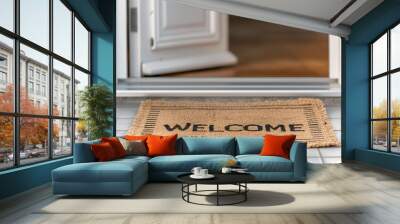 A close-up of a doormat with the word 'WELCOME' written on it, placed in front of an open door. Wall mural