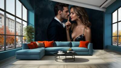 A couple in elegant attire, with the woman holding her finger to the man's lips. Wall mural