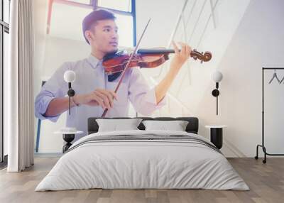 A musician man is practicing the violin playing with the melodiousness at stairway. Selected focus. Wall mural