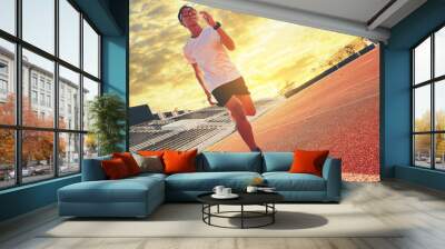 Fit young man running sprinting at the racetrack. Fit runner fitness runner during outdoor workout at racetrack. Start running concept. Wall mural