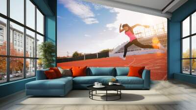 Fit young man running sprinting at the racetrack. Fit runner fitness runner during outdoor workout at racetrack. Start running concept. Wall mural