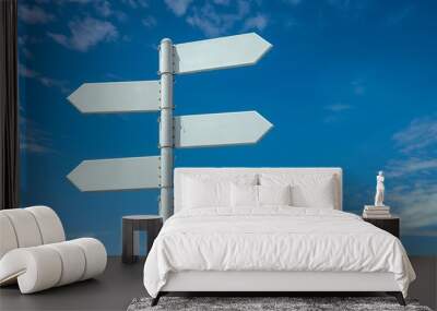 Image of five blank white road signs pointing in different directions against a bright blue sky with scattered clouds. Wall mural