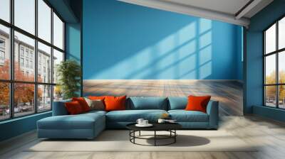 Sunlit empty room with vibrant blue walls and polished wooden floor. Wall mural