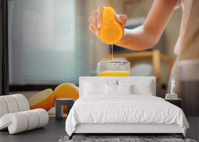 Woman hand squeezes juice from fresh orange, Homemade a glass of orange juice Wall mural