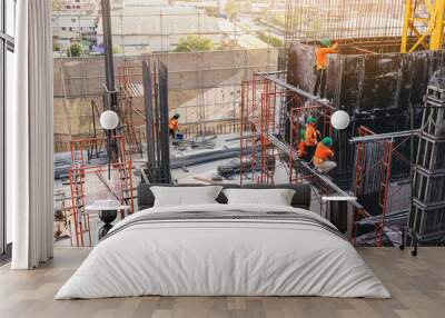 Workers are working on construction site, labourers wearing vest and safety helmet, construction crews on steel work at the building Wall mural