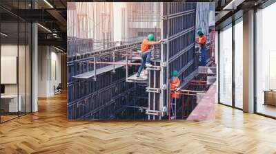 Workers are working on construction site, labourers wearing vest and safety helmet, construction crews on steel work at the building Wall mural