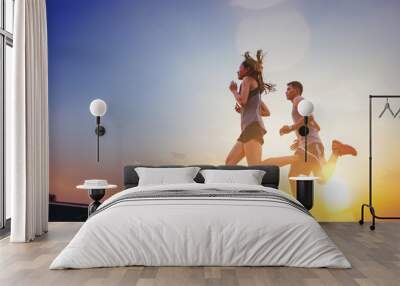 Young couples running sprinting on road. Fit runner fitness runner during outdoor workout with sunset background Wall mural