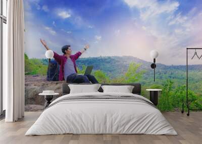 Young success man using laptop and open arms on mountain peak celebrate his freedom Wall mural