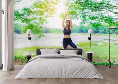 Young woman doing yoga pose under the tree close the nature Wall mural