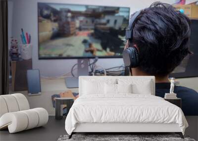 back view of young gamer playing fps video games at home Wall mural