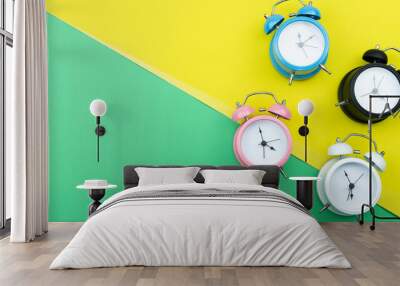 Flat lay retro beautiful new alarm clock on green and yellow paper background. Wall mural