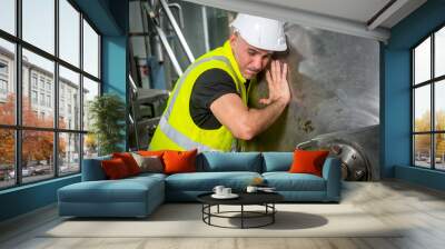 A technician in a beverage factory wearing a uniform and helmet checks the readiness of the high-pressure boiler before operating the machine Wall mural