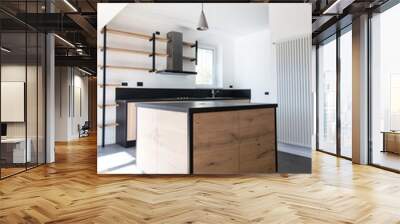 New kitchen in oak and black granite and stainless steel with island, sink, doors, shelves and extractor hood. Industrial design cuisine in a renovated apartment with gray concrete flooring. Cookery Wall mural