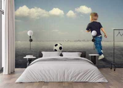 A little boy playing football outdoors. Wall mural