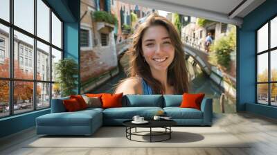 Smiling woman takes a selfie in Venice, Italy, with picturesque canals and charming architecture in the background on a sunny day. Wall mural