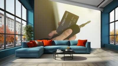 The young man paid the car debt by paying with a credit card with a car key in his hand. Wall mural