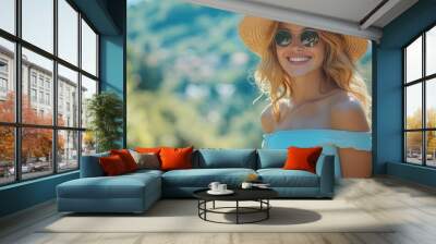 Young woman with sunglasses and a straw hat smiling outdoors in nature during the summer Wall mural