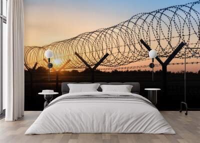 Silhouette of a barbed wire fence steel jail  with the sunset in the background Wall mural