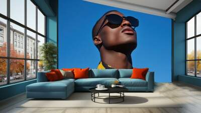 Stylish model in striped shirt and sunglasses under blue sky. Wall mural