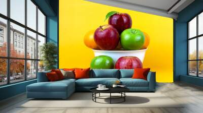 Healthy fruits, green apples, red apples, oranges isolated on yellow background. Creative composition of colorful of fruits isolated on yellow background, Close up view Wall mural