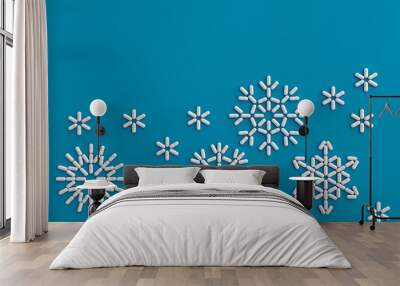 A lot of pills scattered on a blue background in the form of snowflakes . 3D illustration Wall mural