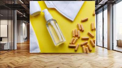 Sanitizer, protective mask and pills on a yellow background Wall mural