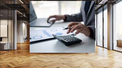 Close up view of  Businessman using a calculator to calculate financial accounts at his office desk. Wall mural