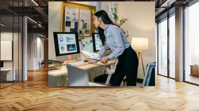 Focused businesswoman analyzing data at desk in modern office, strategizing for small business growth with determined look Wall mural