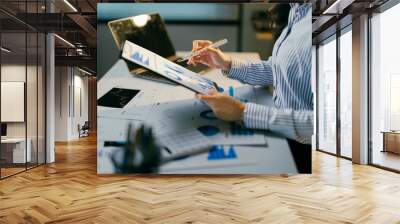 Focused businesswoman analyzing financial data in office, pointing at charts on laptop. Strategizing for company growth with precision and expertise Wall mural