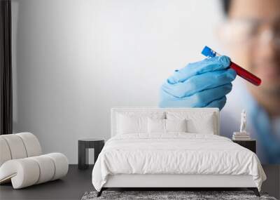 lab technician with a tube of blood sample and a rack with other samples / lab technician holding blood tube sample for study. Wall mural