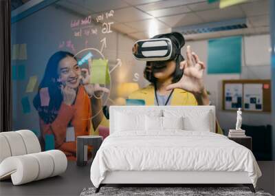 Two young businesswomen are brainstorming ideas for a new project, using a virtual reality headset and writing on a glass board with colorful sticky notes Wall mural