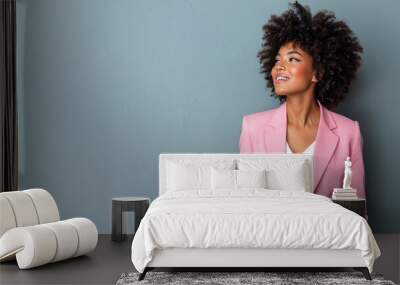 Afro business woman in pink suit smile looking up isolated on gray Wall mural